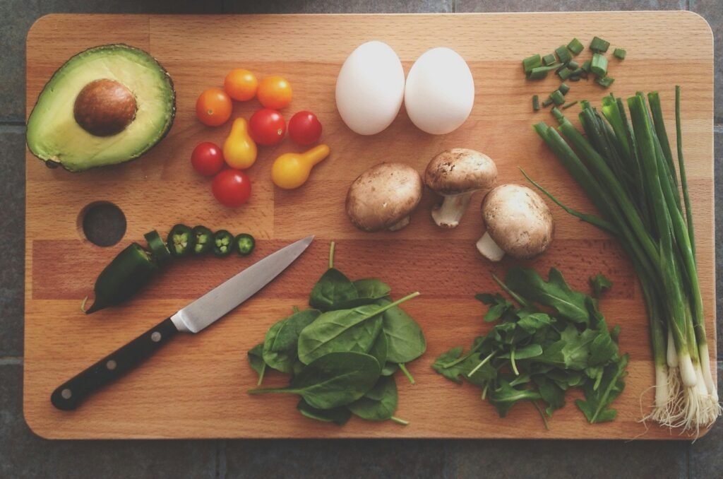 zdjęcie warzyw i ugotowanych jajek ułożonych na drewnianej desce obok noża - wszystkie produkty bez laktozy i nabiału