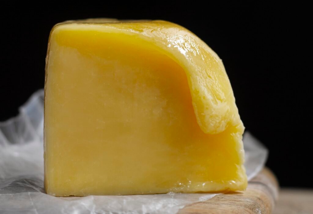 masło klarowane Blok żółtego masła klarowanego na papierze pergaminowym, z lekko stopioną i błyszczącą powierzchnią.