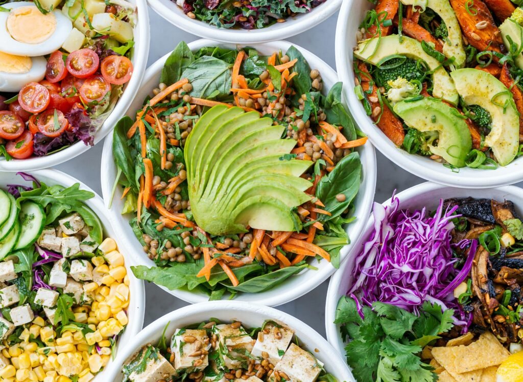 Kolorowe miski sałatek warzywnych z awokado, tofu, jajkiem i świeżymi dodatkami – zdrowy posiłek bez laktozy.