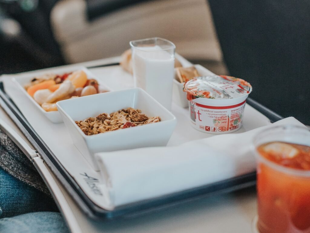 Zestaw posiłku serwowanego w samolocie – musli, owoce, jogurt i szklanka mleka na tacy pokładowej