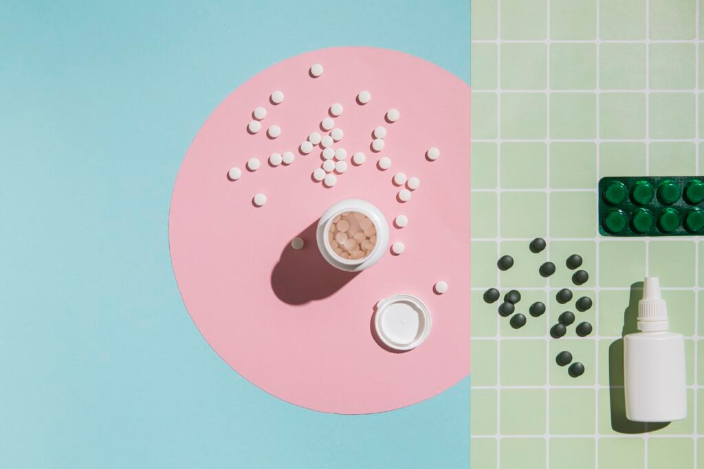 Ukryta laktoza w suplementach i lekach – różne tabletki, kapsułki i buteleczka z kroplami na pastelowym tle, symbolizujące produkty, które mogą zawierać laktozę.